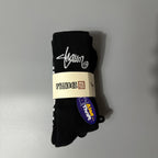 A pair of black knit socks bundled with a paper band, featuring a white script logo and a blue 'Alad Theft' tag, set against a plain gray background.